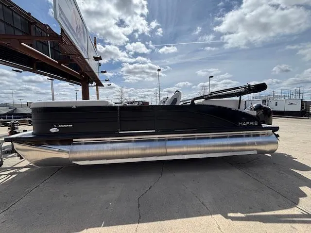 Slide: The Image of 2025 Harris Sunliner 230 pontoon boat parked outdoors under a cloudy sky. - 1