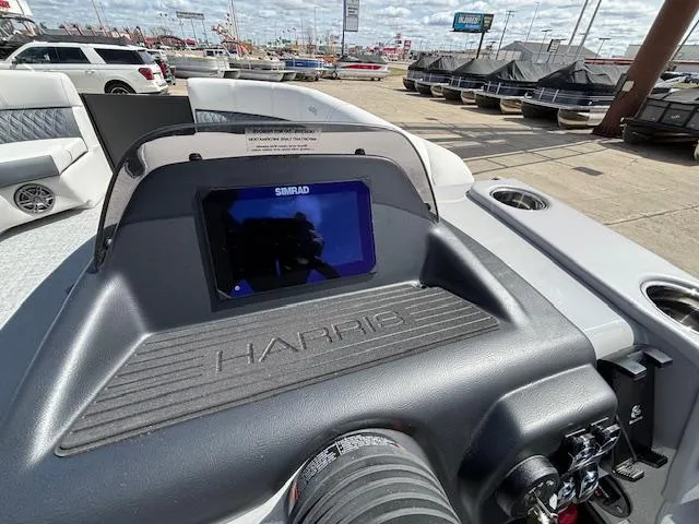 Slide: The Image of 2025 Harris Sunliner 230 boat dashboard with Simrad display in a marina setting. - 26