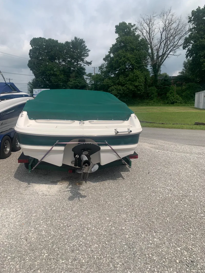 Slide: The Image of 2000 Chaparral 196 SSi boat with green cover, parked on gravel. - 2