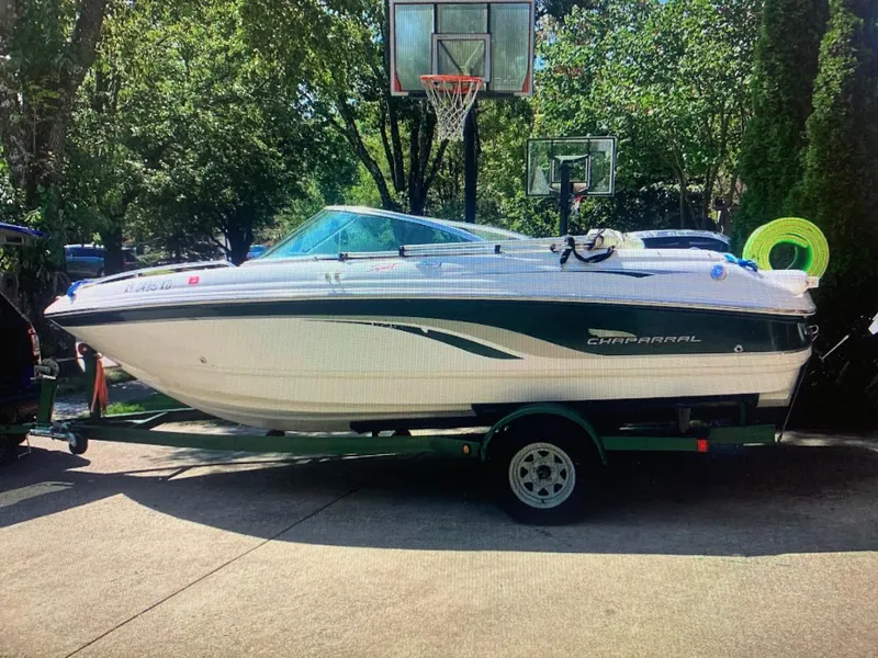 Slide: The Image of 2000 Chaparral 196 SSi boat on trailer in driveway, surrounded by trees. - 5