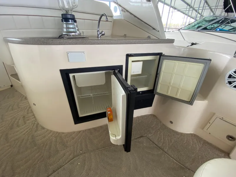 Slide: The Image of 2006 Rinker 360 Fiesta Vee boat interior with open mini fridge and sink. - 12
