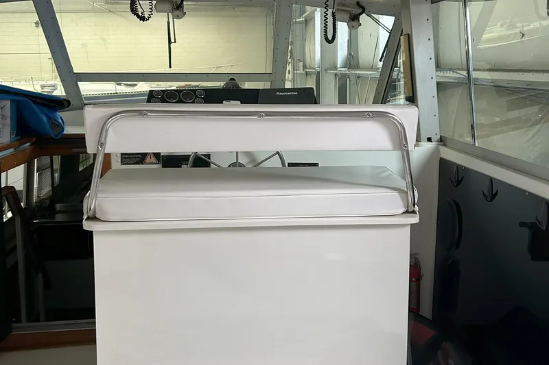 Slide: The Image of 1977 Bertram 42 Motor Yacht helm with white cushioned seat and navigation equipment. - 19
