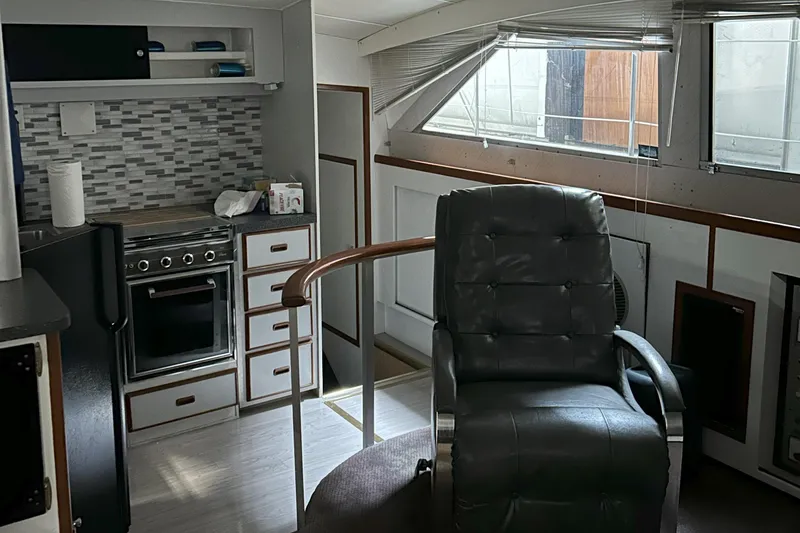 Slide: The Image of 1977 Bertram 42 Motor Yacht interior with kitchen, leather chair, and large window. - 2