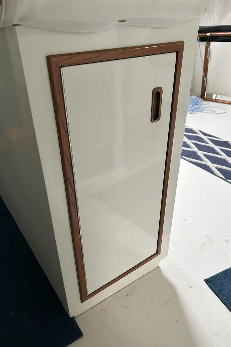 Slide: The Image of 1977 Bertram 42 Motor Yacht interior cabinet with wooden trim and sleek white finish. - 25