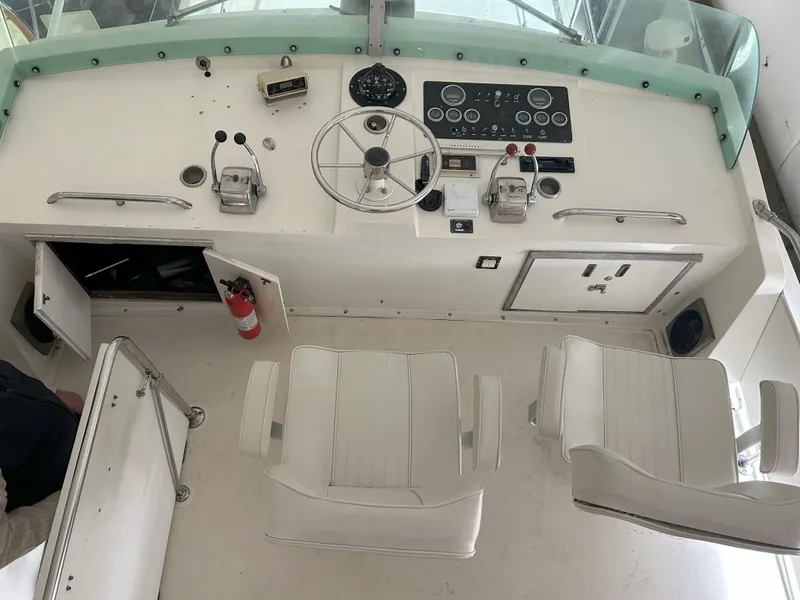 Slide: The Image of 1977 Bertram 42 Motor Yacht helm with steering wheel, controls, and white captain chairs. - 4