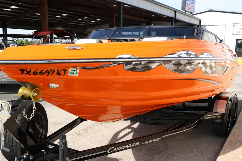 Slide: The Image of 2022 Crownline 220 SS LPX boat, vibrant orange with checkered flag design, on a trailer. - 7