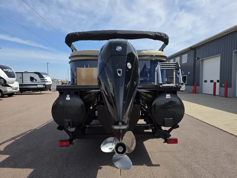 Slide: The Image of 2025 Regency 230 DL3 pontoon boat with powerful outboard motor, parked outdoors. - 2