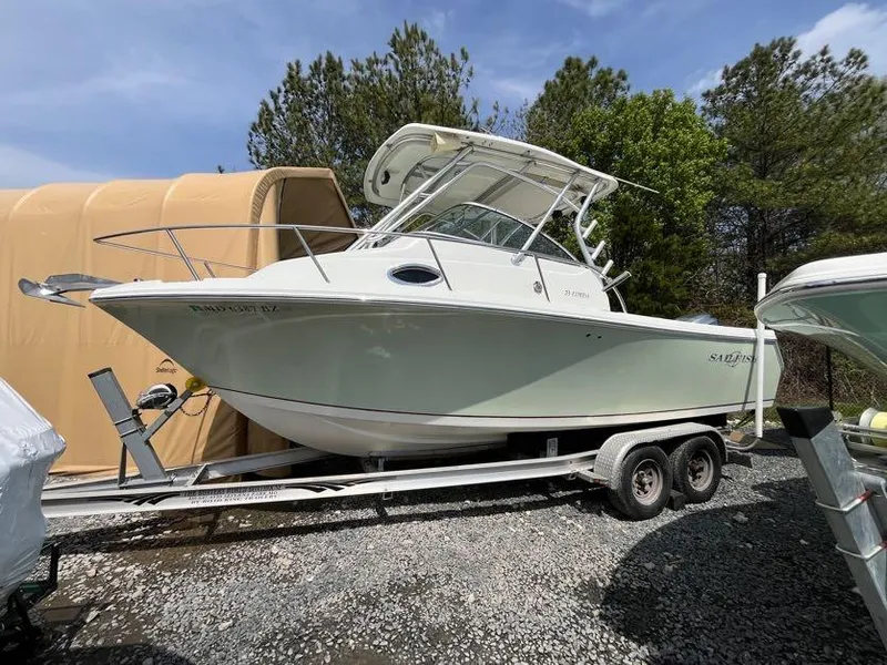 Slide: The Image of 2008 Sailfish 2360 WAC boat on trailer, parked outdoors, surrounded by trees. - 1