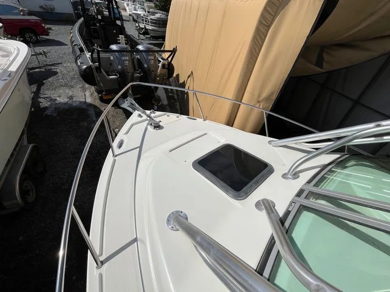 Slide: The Image of 2008 Sailfish 2360 WAC boat deck with railing and hatch, parked near other boats. - 11