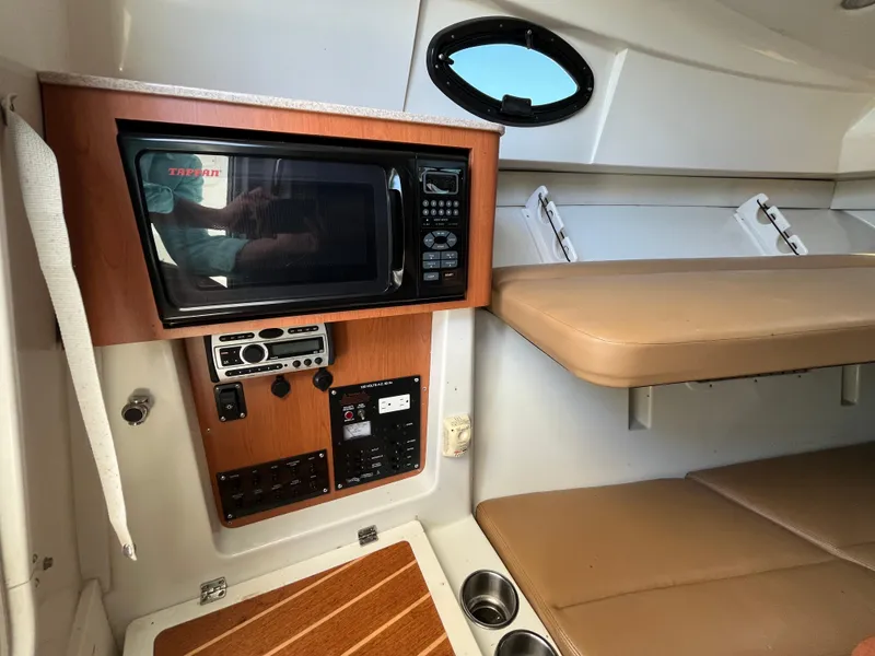Slide: The Image of 2008 Sailfish 2360 WAC cabin interior with microwave, control panel, and seating area. - 18