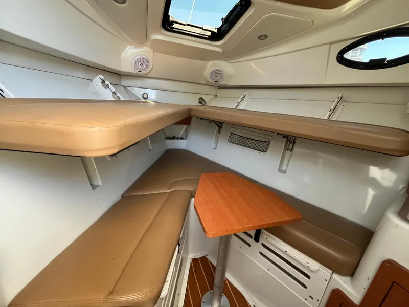 Slide: The Image of 2008 Sailfish 2360 WAC cabin interior with tan seating and wooden table. - 19
