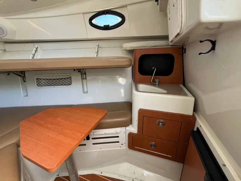 Slide: The Image of 2008 Sailfish 2360 WAC cabin interior with seating, table, sink, and storage. - 20
