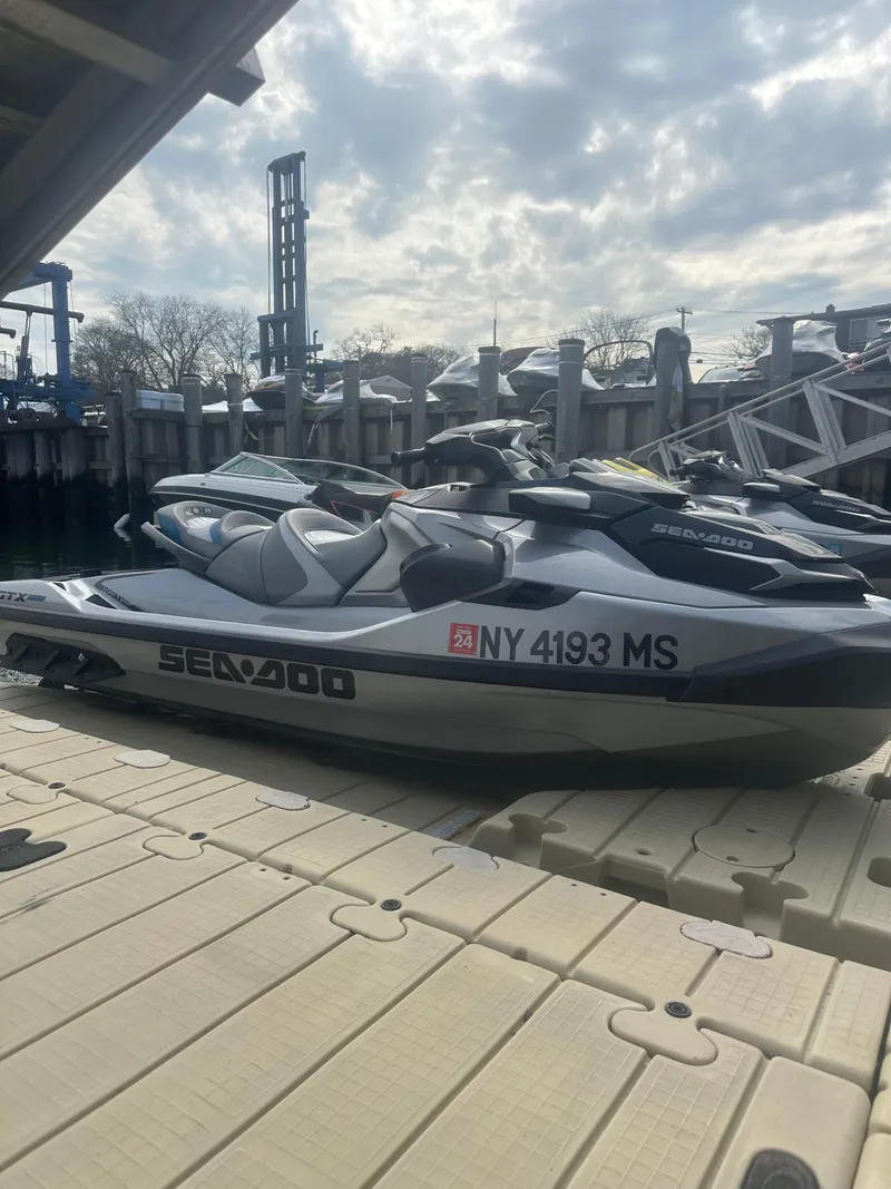 Slide: The Image of 2021 Sea-Doo GTX Limited 300 jet ski docked at a marina under a cloudy sky. - 1