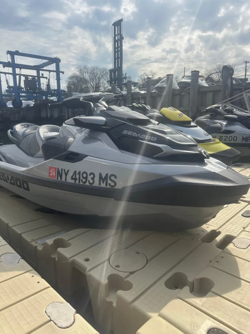 Slide: The Image of 2021 Sea-Doo GTX Limited 300 jet ski on dock under cloudy sky. - 2