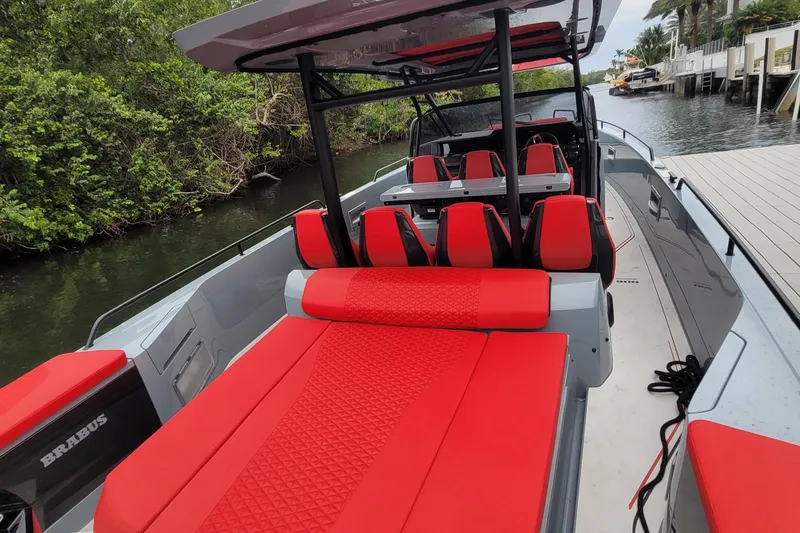 Slide: The Image of 2022 Axopar Brabus Shadow 900 ST with vibrant red seating, docked by lush greenery. - 3
