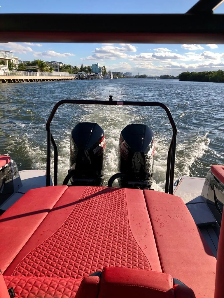 Slide: The Image of 2022 Axopar Brabus Shadow 900 ST with red seating, cruising on a sunny waterway. - 2