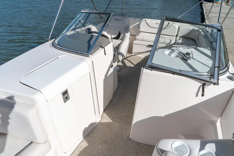 Slide: The Image of 2002 Ebbtide 2400 Mystique Fun Cruiser interior with seating and steering, docked by the water. - 14
