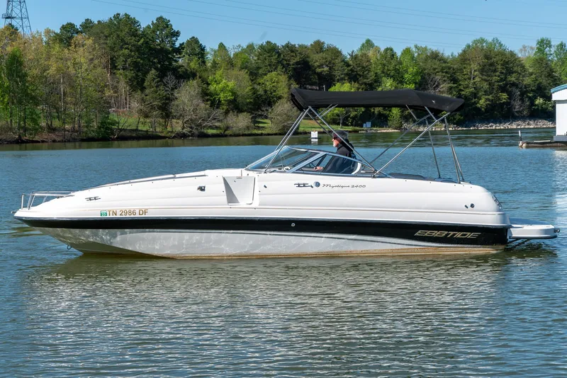 Slide: The Image of 2002 Ebbtide 2400 Mystique Fun Cruiser on a serene lake with lush green trees. - 4
