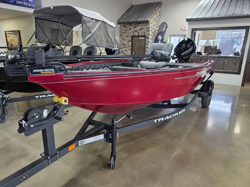Slide: The Image of 2025 Tracker Super Guide V 16 T boat in showroom, red hull, on trailer. - 9