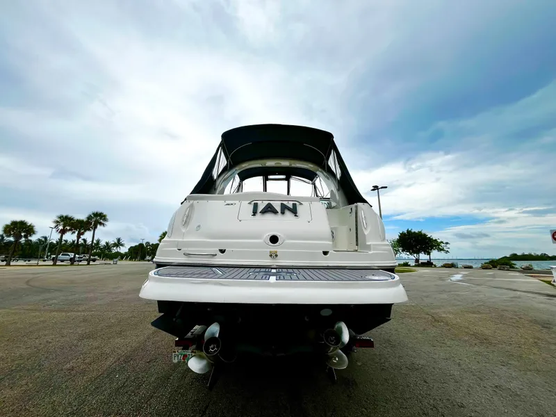Slide: The Image of 2005 Sea Ray 280 Sundancer boat on trailer, parked near waterfront under cloudy sky. - 2