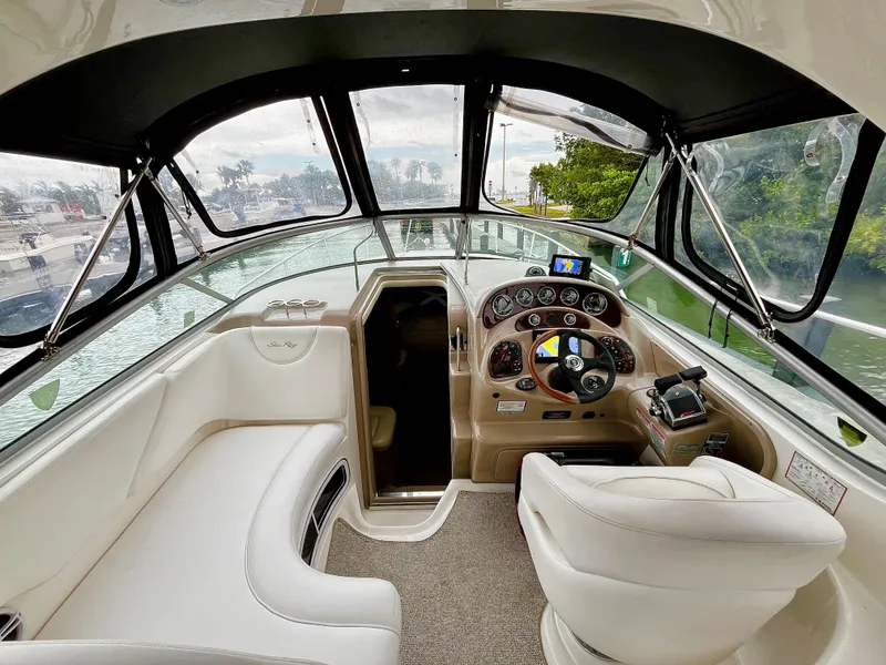 Slide: The Image of 2005 Sea Ray 280 Sundancer cockpit with steering wheel, dashboard, and white seating. - 29