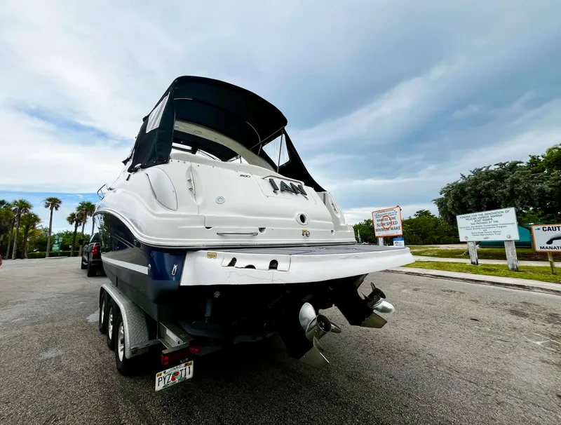 Slide: The Image of 2005 Sea Ray 280 Sundancer boat on trailer, parked near palm trees and caution signs. - 3