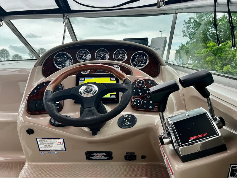 Slide: The Image of 2005 Sea Ray 280 Sundancer helm with steering wheel, gauges, and Mercury controls. - 32