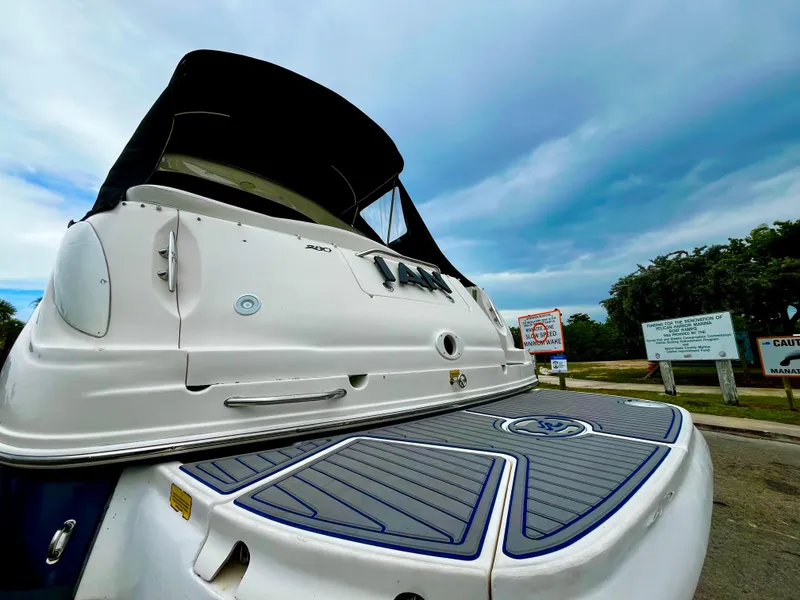 Slide: The Image of 2005 Sea Ray 280 Sundancer boat with black canopy, docked under cloudy sky. - 4