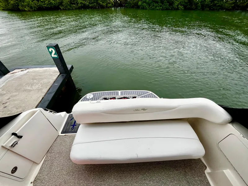 Slide: The Image of 2005 Sea Ray 280 Sundancer boat at dock, featuring white seating and calm water backdrop. - 43