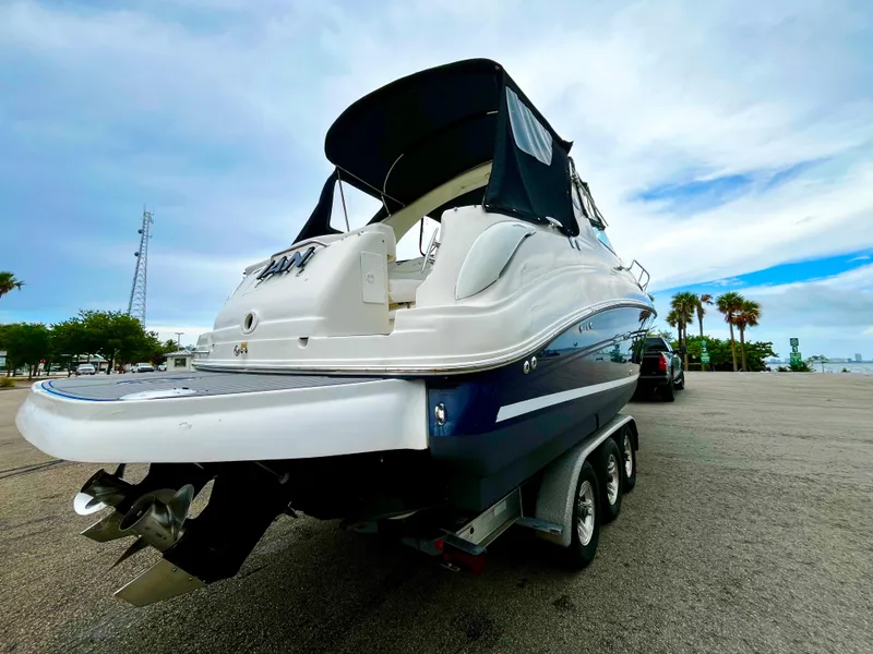 Slide: The Image of 2005 Sea Ray 280 Sundancer boat on trailer, parked near waterfront with palm trees. - 5