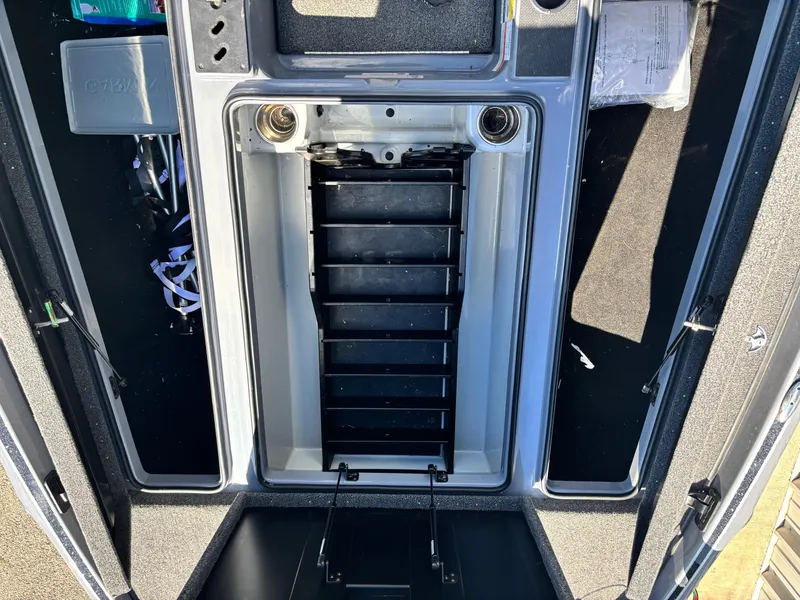 Slide: The Image of 2024 Triton 19 TrX boat storage compartment with organized tackle trays and accessories. - 7