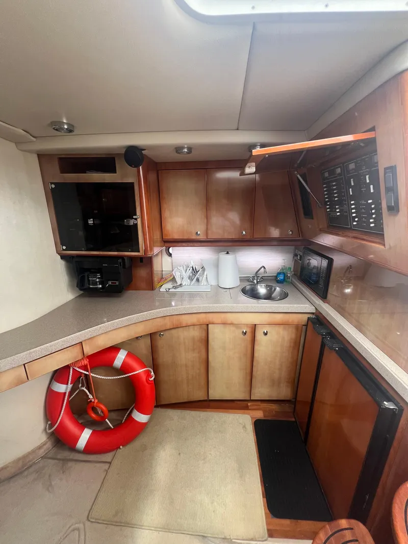 Slide: The Image of 2003 Regal Commodore 4260 yacht interior with kitchenette, wooden cabinets, and life preserver. - 27