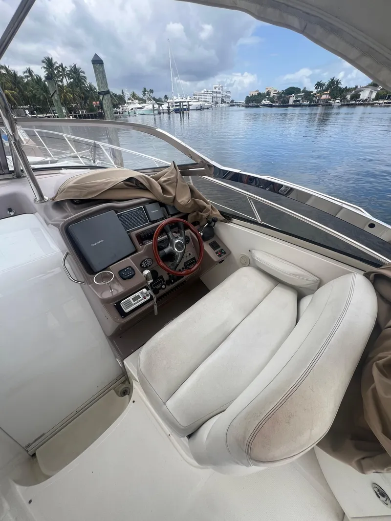 Slide: The Image of 2003 Regal Commodore 4260 yacht cockpit with steering wheel, docked by calm waters. - 43