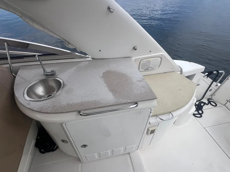 Slide: The Image of 2003 Regal Commodore 4260 yacht kitchenette with sink, countertop, and storage by the water. - 45