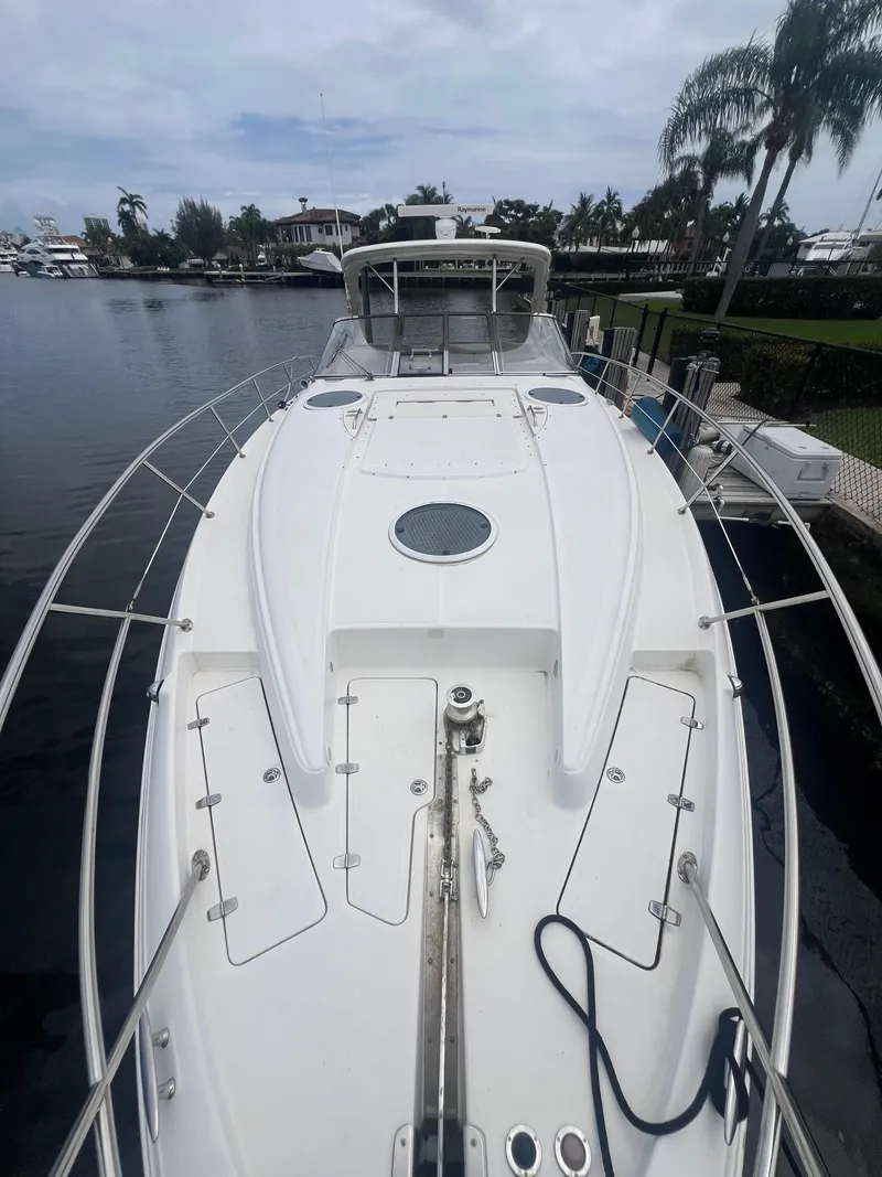 Slide: The Image of 2003 Regal Commodore 4260 yacht docked by a waterfront, showcasing sleek design and spacious deck. - 56