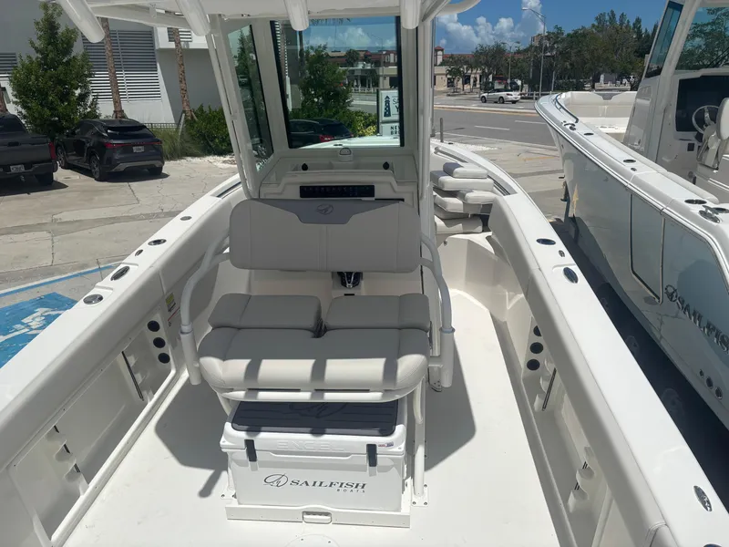 Slide: The Image of 2026 Sailfish 232 CC boat interior with seating and console, parked outdoors. - 10