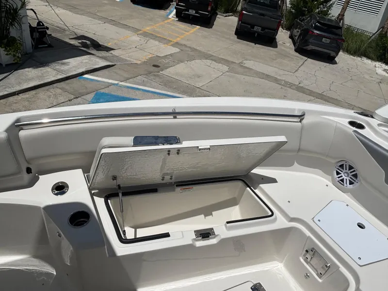 Slide: The Image of Open storage compartment on 2026 Sailfish 232 CC boat deck, with cup holders and speaker. - 17