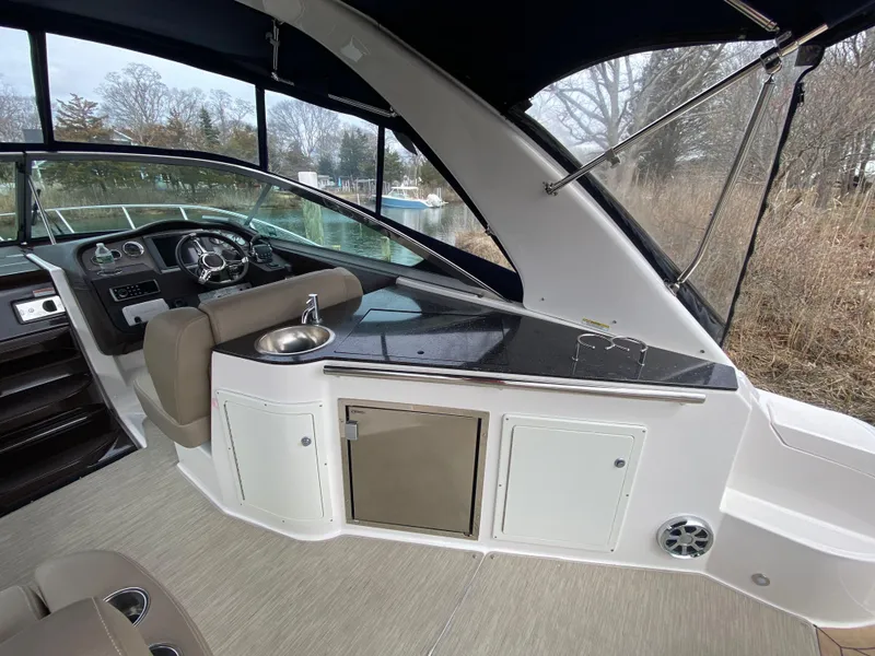 Slide: The Image of 2015 Regal 32 Express boat interior with helm, seating, and kitchenette area. - 14