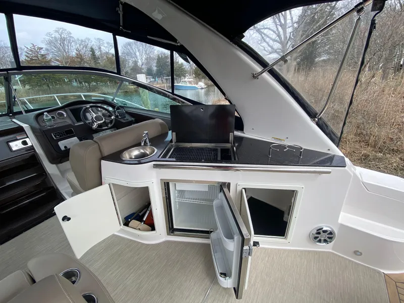 Slide: The Image of 2015 Regal 32 Express boat interior with kitchenette, sink, and seating area. - 15