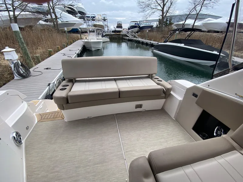 Slide: The Image of 2015 Regal 32 Express boat interior with beige seating at a marina dock. - 19