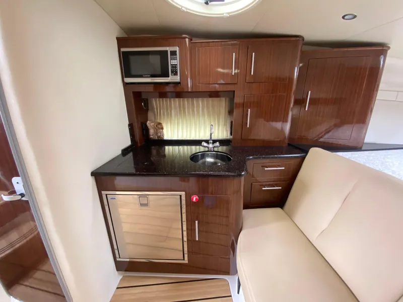 Slide: The Image of Compact kitchen area in a 2015 Regal 32 Express boat with wood cabinetry and modern appliances. - 24