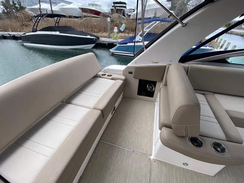 Slide: The Image of 2015 Regal 32 Express boat interior with beige seating and cup holders, docked by the water. - 25