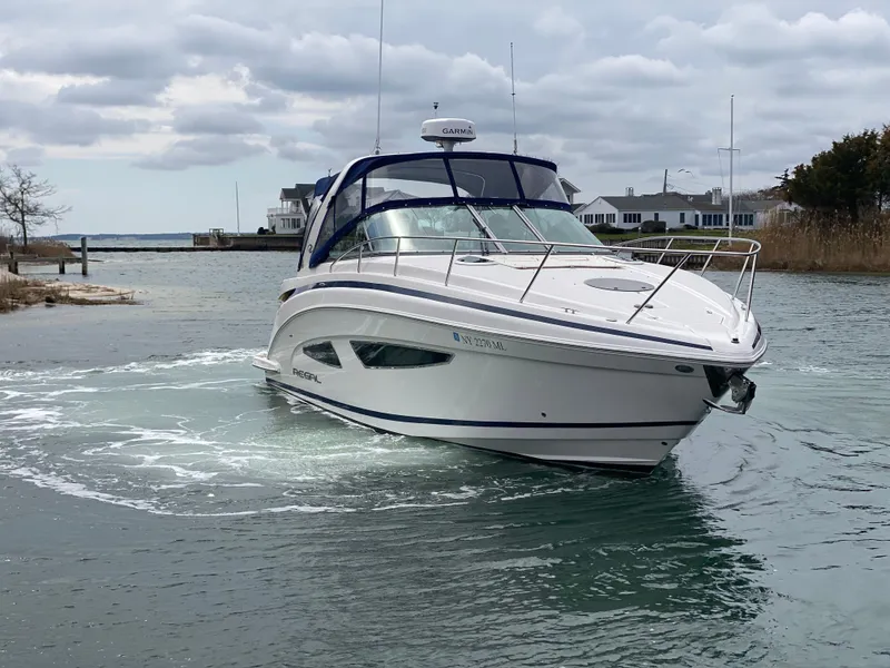 Slide: The Image of 2015 Regal 32 Express boat navigating a calm waterway under cloudy skies. - 5