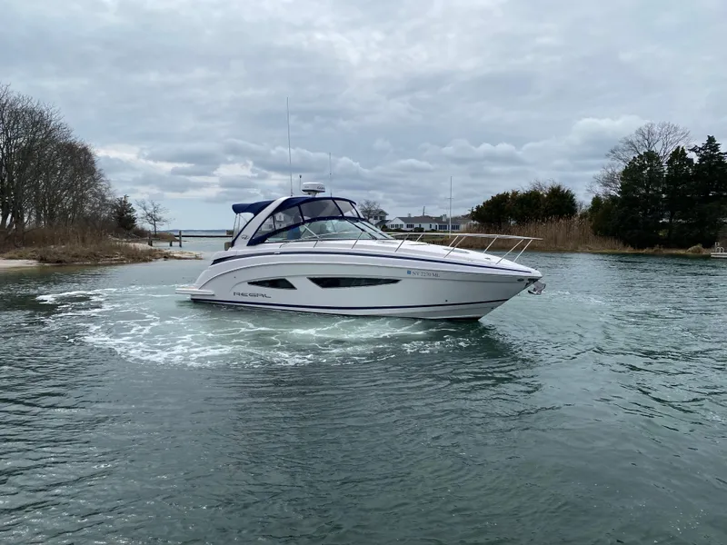 Slide: The Image of 2015 Regal 32 Express boat cruising on a calm, scenic waterway. - 6