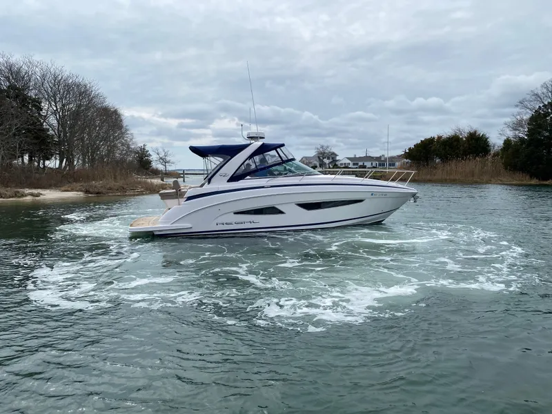 Slide: The Image of 2015 Regal 32 Express boat cruising on a calm waterway under cloudy skies. - 8