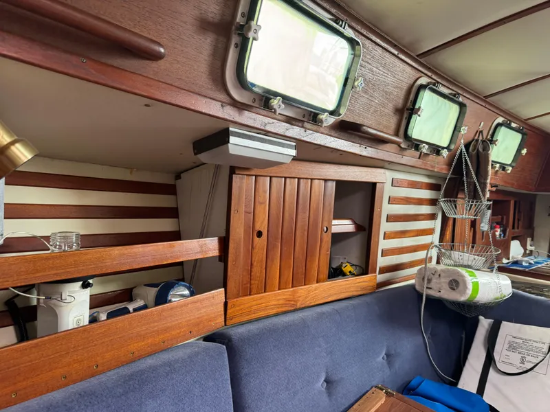 Slide: The Image of 1984 Endeavour 33 yacht interior with wooden cabinets and blue seating. - 8