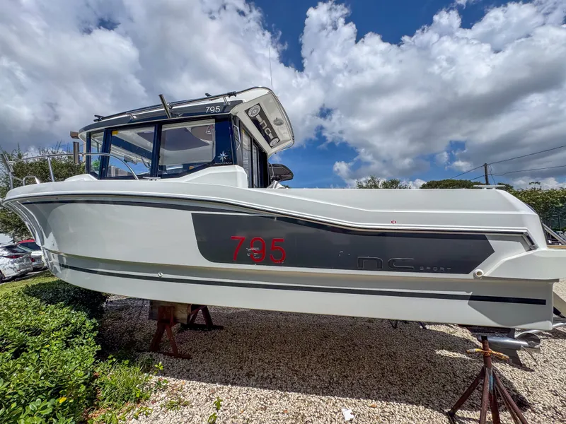 Slide: The Image of 2022 Jeanneau NC795 Sport boat displayed outdoors under a cloudy sky. - 0