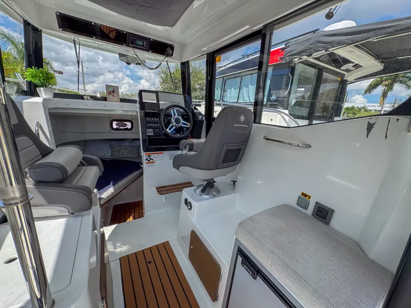 Slide: The Image of 2022 Jeanneau NC795 Sport interior with modern helm, seating, and wood accents. - 12