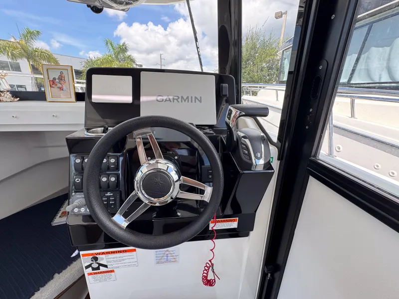 Slide: The Image of 2022 Jeanneau NC795 Sport helm with Garmin navigation system and steering wheel. - 16