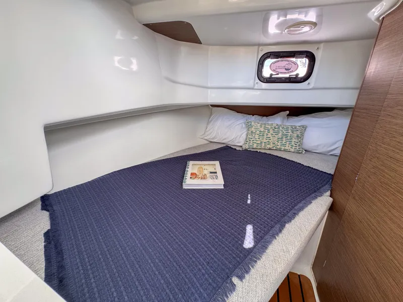 Slide: The Image of Cozy cabin interior of 2022 Jeanneau NC795 Sport with bed, pillows, and window. - 19